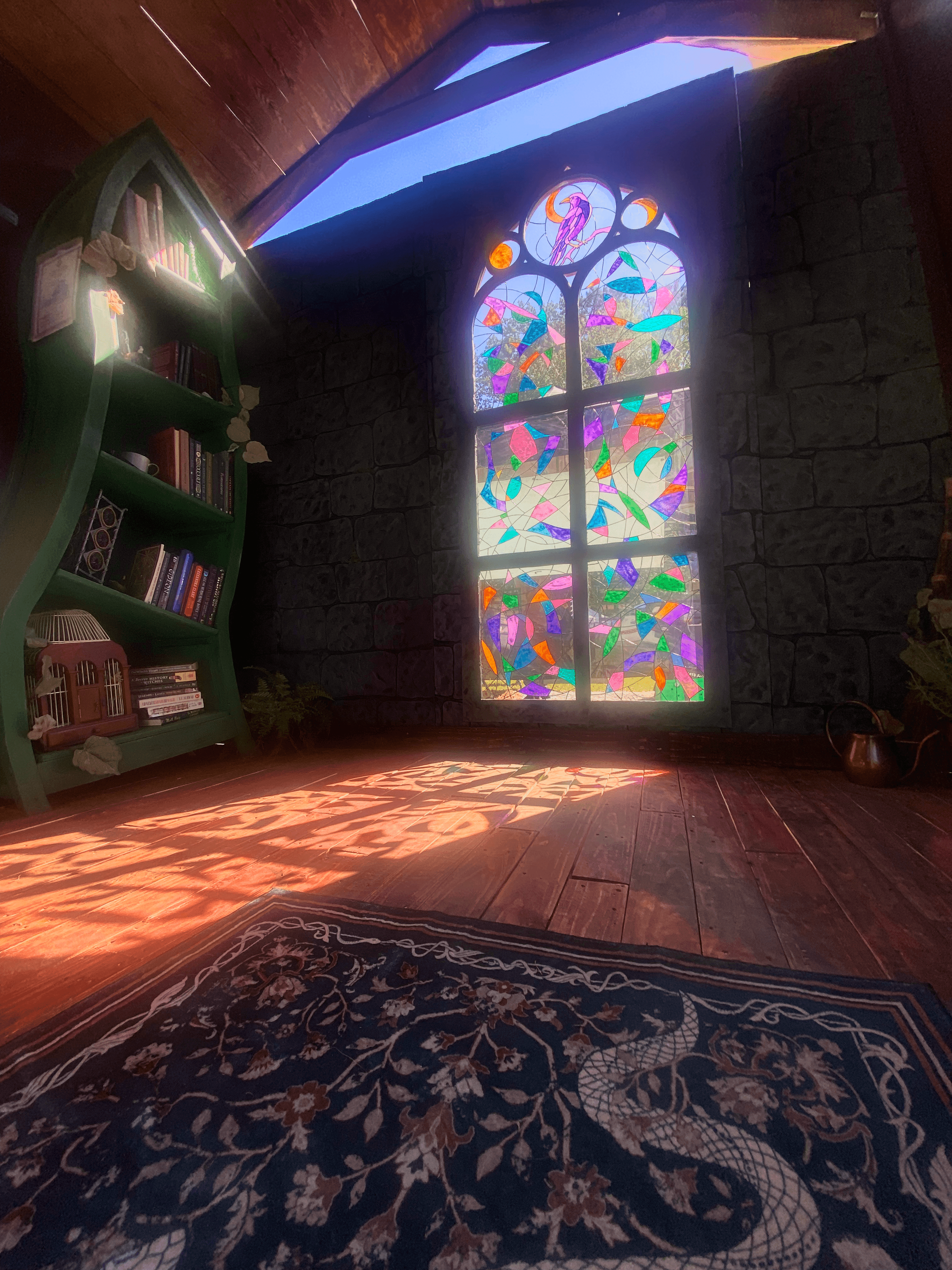 Sunlight coming through faux stained glass window onto whimsical bookshelf at Richmond Ren Faire 2026